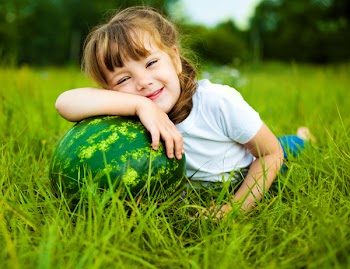 cute little girl with a water-melon on the grass in summertime