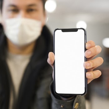 Defocused man with medical mask holding up&nbsp; phone Free Photo