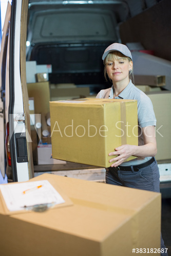 Deliverywoman lifting box outside delivery van