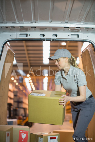 Deliverywoman lifting boxes inside delivery van