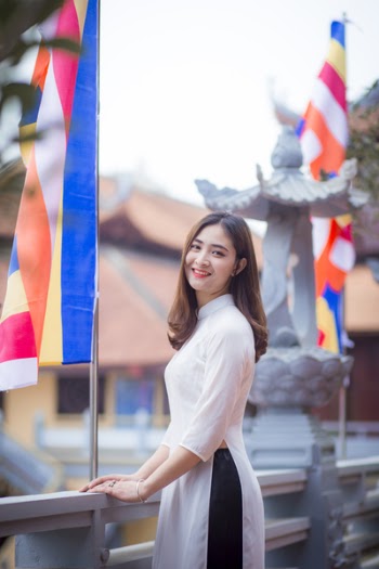 Depth of Field Photo of Woman Wearing White Dress Standing Near Flag Pole