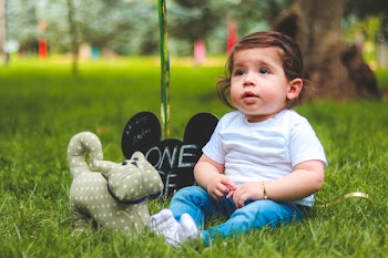 Depth of Field Photography of Baby Sitting on Green Grass