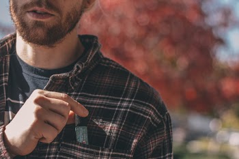 Depth of Field Photography of Person Wearing Brown Plaid Sport Shirt Holding Pen in Pocket