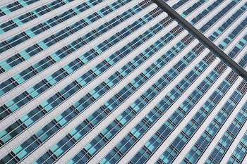 Detail photo of a skyscraper's many windows reflecting the blue sky