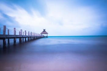 dock on body of water under cloudy sky