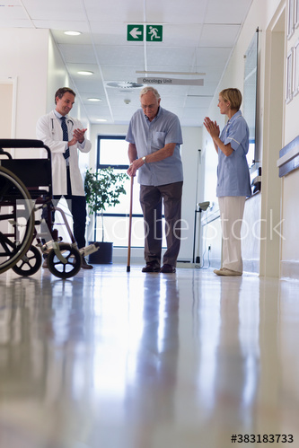 Doctor and nurse clapping for senior man walking with cane in hospital
