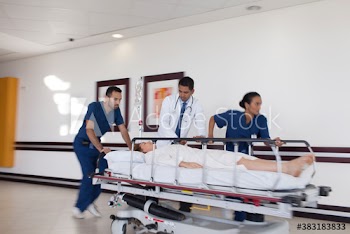 Doctor and nurses rushing patient on stretcher in hospital corridor