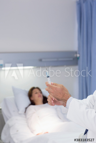 Doctor preparing syringe for patient in hospital room