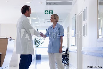 Doctor shaking hands with nurse in hospital corridor