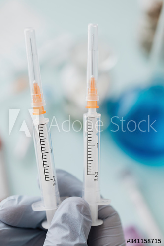Doctor wearing latex gloves holding syringes