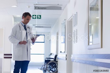 Doctor with digital tablet making rounds in hospital corridor