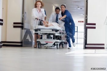 Doctors and nurse rushing patient on stretcher in hospital corridor