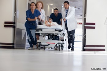 Doctors and nurses rushing patient on stretcher in hospital corridor