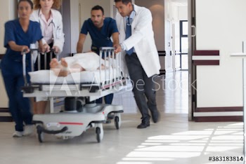 Doctors and nurses rushing patient on stretcher in hospital corridor