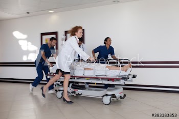 Doctors and nurses rushing patient on stretcher in hospital corridor