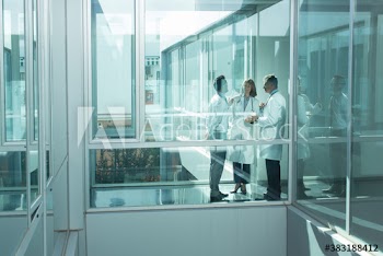 Doctors consulting in sunny modern office corridor