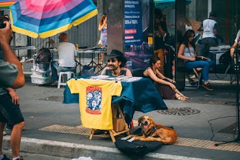 Dog Laying On Pavement Beside Man Sitting 