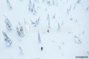 Drone shot of people trekking in a snowy forest in Lapland, Finland