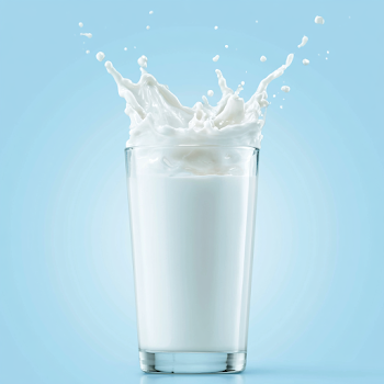 Dynamic Milk Splash in Glass against Sky Blue Background