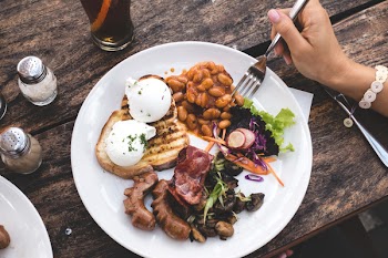 Eating high protein brunch with poached eggs, beans and bacon 