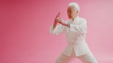 Elderly Chinese Tai Chi Practitioner Dances in Pink Studio Setting Elderly Chinese Tai Chi Practitioner Dances in Pink Studio Setting