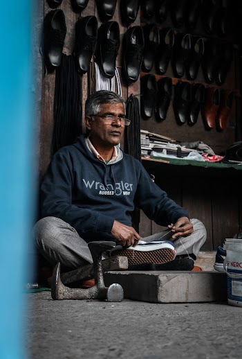 Elderly Man In His Shop Repairing Shoes
