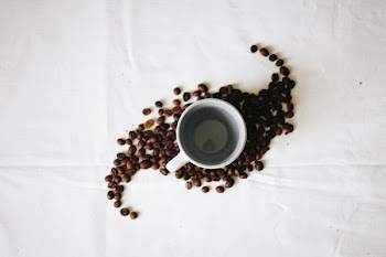 Empty White Ceramic Mug Surrounded by Coffee Grounds