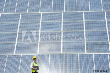 Engineer standing below sunny solar panels
