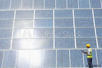 Engineer with laptop examining sunny solar panels