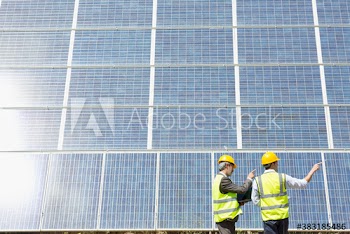 Engineers talking below sunny solar panels