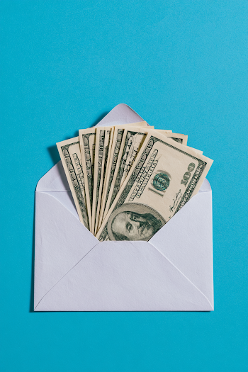 Envelope Stuffed with Hundred-Dollar Bills on Turquoise Background