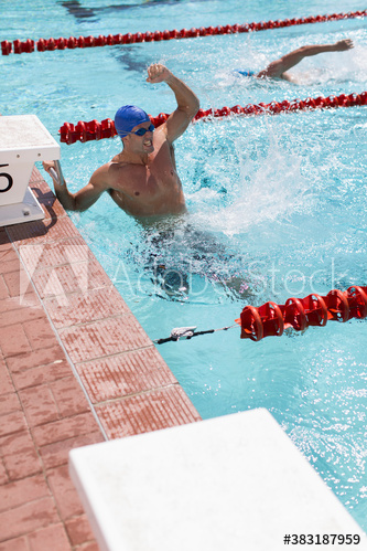 Excited male swimmer celebrating victory in sunny swimming pool