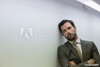 Exhausted corporate businessman leaning against wall