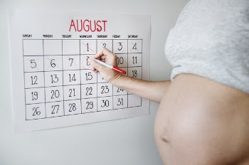 Expectant Lady Holding Pen Marking Calendar