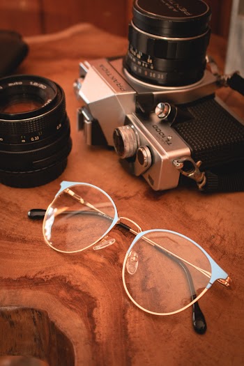 Eyeglasses And Camera On Brown Wooden Surface Close-up Photography