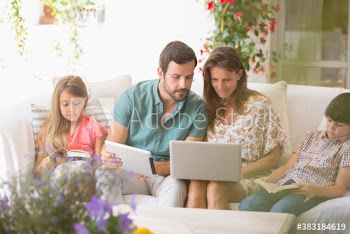 Family reading books and using laptop and digital tablet on patio