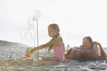 Family relaxing and building sandcastle on sunny beach