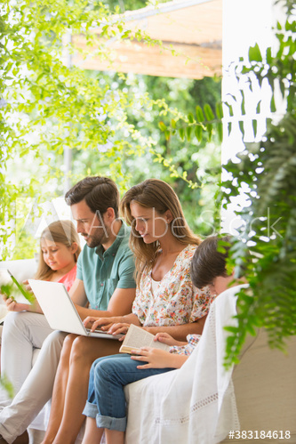 Family relaxing with book and laptop on patio