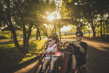 Family Riding on Red Cart Near Trees