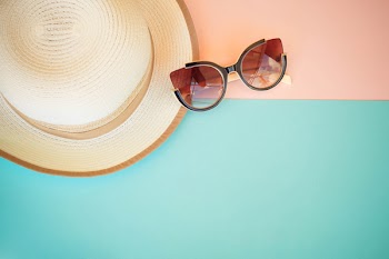 Fashionable hat and sunglasses on a multi-colored background.