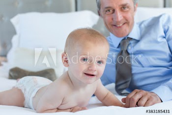 Father and cute baby son on bed