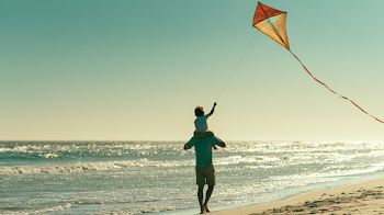 Father and Son Enjoying a Sunny Beach Day with a Kite
