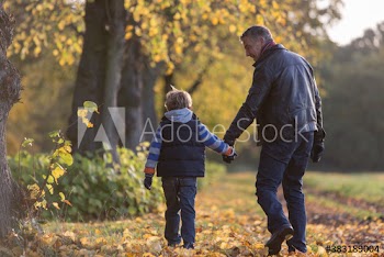 Father and son holding hands walking in autumn park