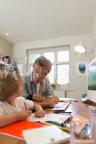 Father and son making faces in home office