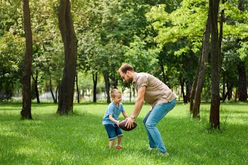 Father and son playing american football at park