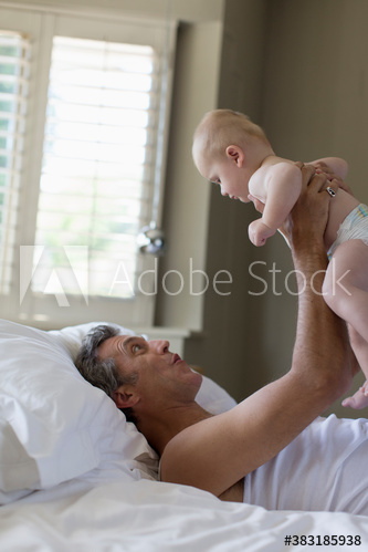 Father holding baby son in bed