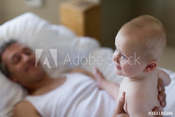 Father holding baby son on bed