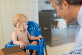Father watching baby son in high chair