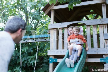 Father watching kids on playground slide