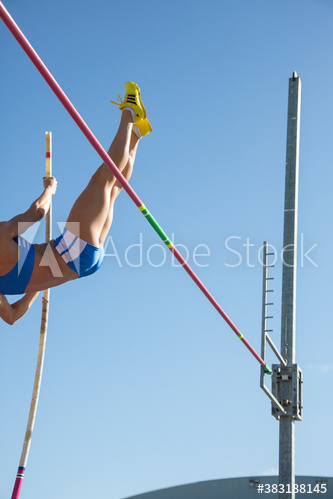 Female athlete pole vaulting under sunny bleu sky